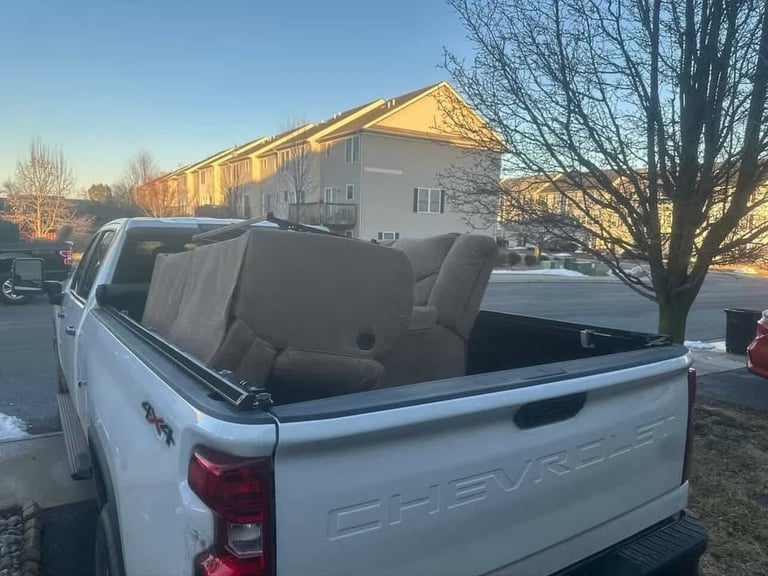 White Chevrolet pickup truck bed with removed tailgate and gray seats, parked in front of an apartment building